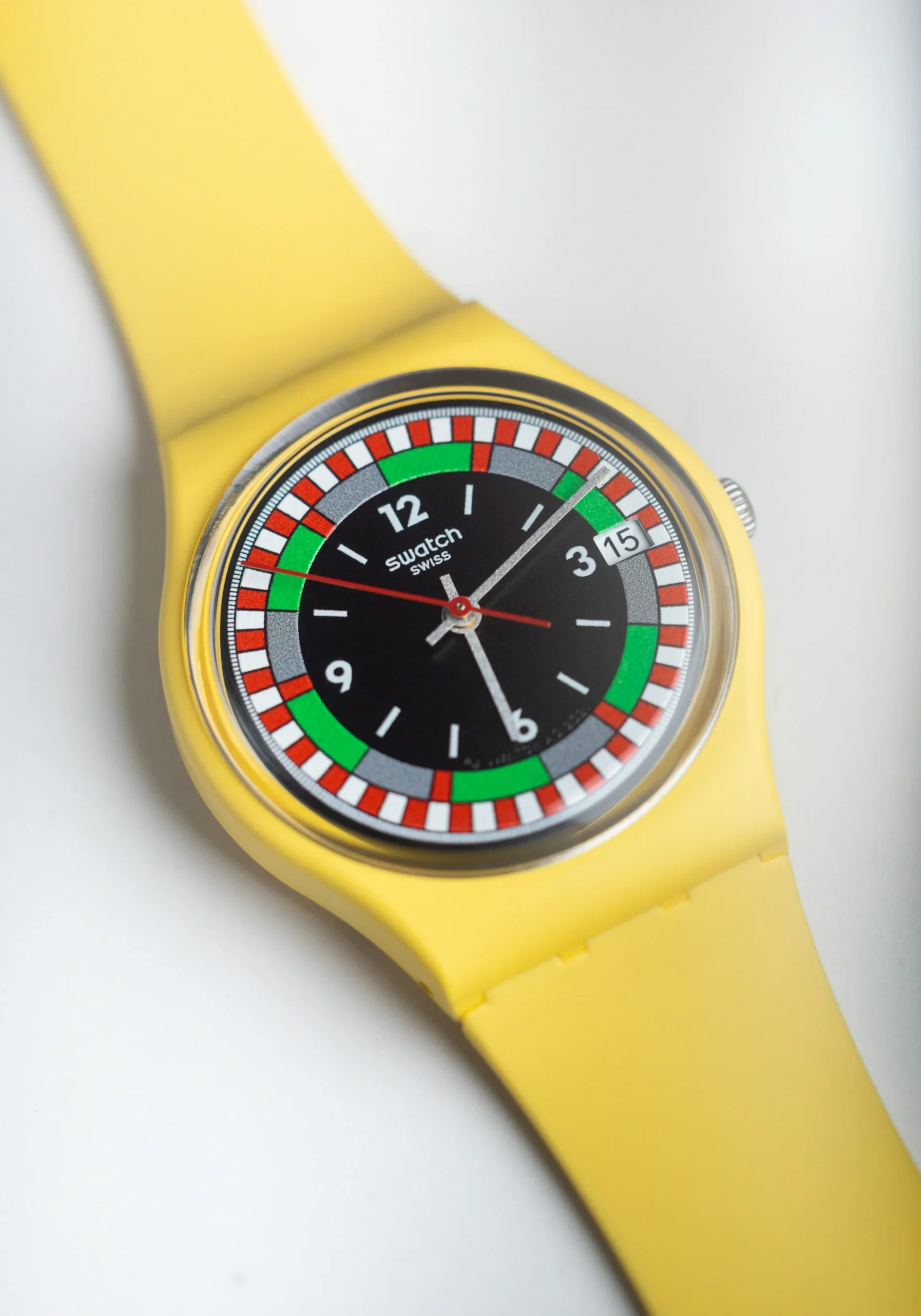 A colorful Swatch casual watch with a vibrant yellow strap, black face, and red, green, and silver details.