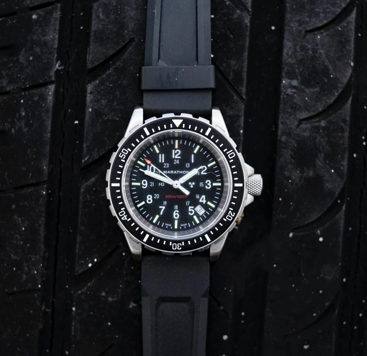 A close-up of a Marathon Military watch featuring a black dial, a black bezel, and a black rubber strap.