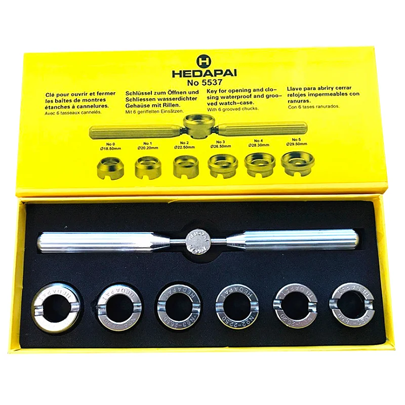 Close-up of an Oyster-style watch back opener with a wrench and six grooved dies resting in a box.