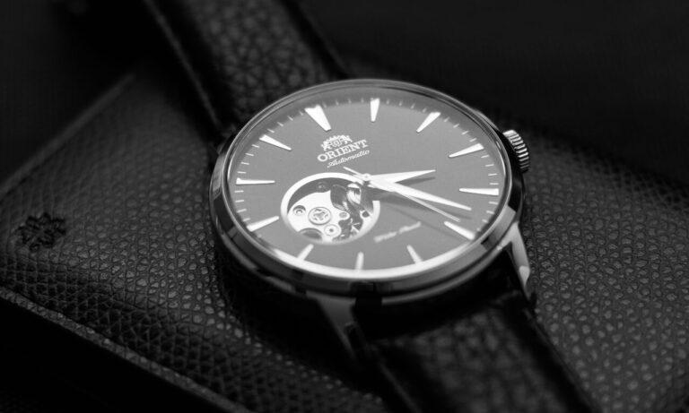 A close-up of the Orient watch features an open-heart dial that showcases its mechanical movement