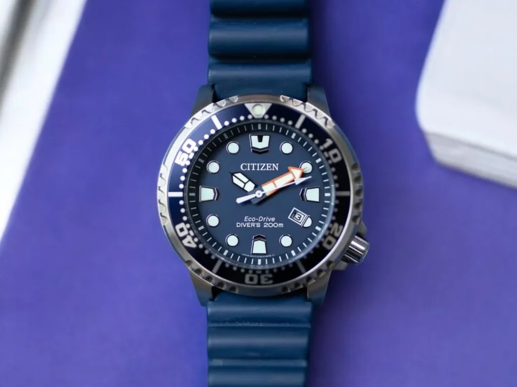 Citizen Promaster Dive BN0151-09L with a rotating bezel, large numeral markers, and date display, set on a blue surface.