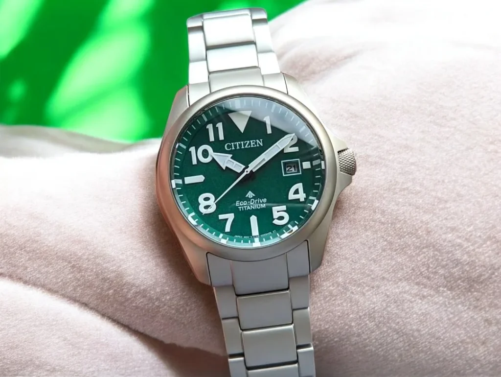 Citizen Promaster Tough BN0241-59W rests on a light pink textured surface with a blurred green background.