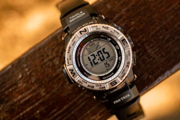 Close-up of a Casio Pro Trek watch resting on a brown wooden desk.