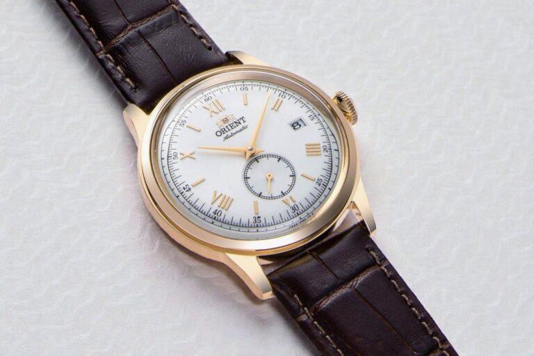 Orient Bambino Version 7 gold-tone watch with a white dial featuring Roman numerals, a date window, and a subdial.