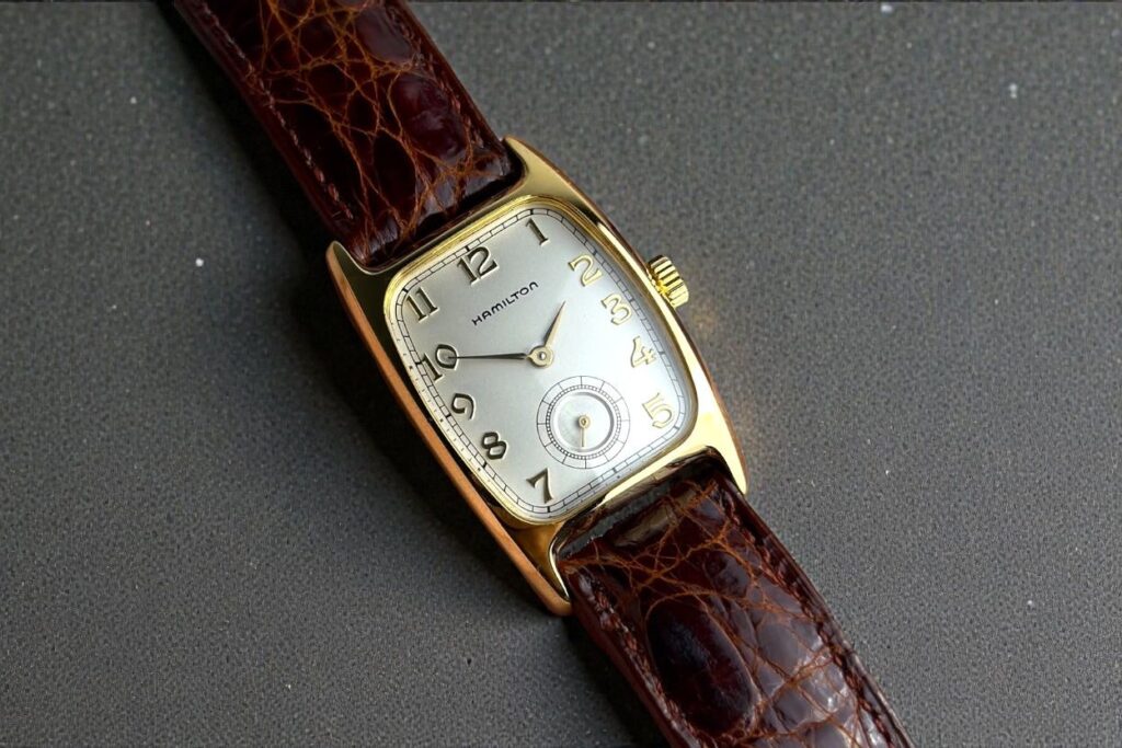 Vintage Hamilton American Classic Boulton wristwatch with a gold rectangular case, silver dial, and brown leather strap.