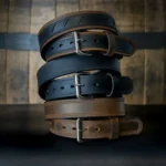 Three distinct leather belts arranged in a stacked formation, showcasing their varied textures and colors.