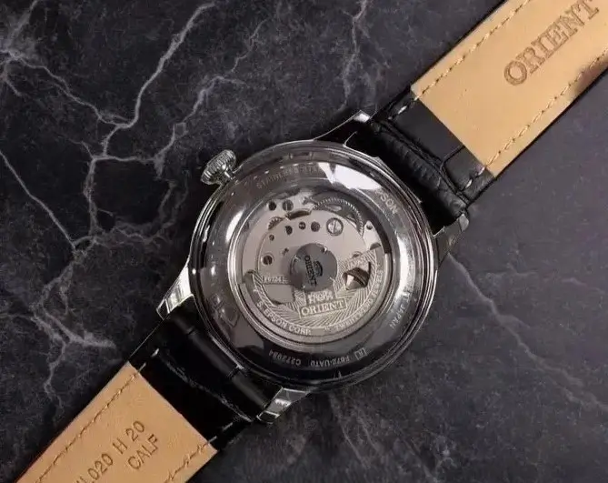 Back view of Orient Bambino 38mm Version 7 automatic watch showing the exhibition caseback on dark gray marble.