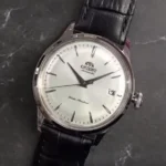 Front view of Orient Bambino 38mm Version 7 watch featuring white dial with silver hands and markers on dark gray marble surface.