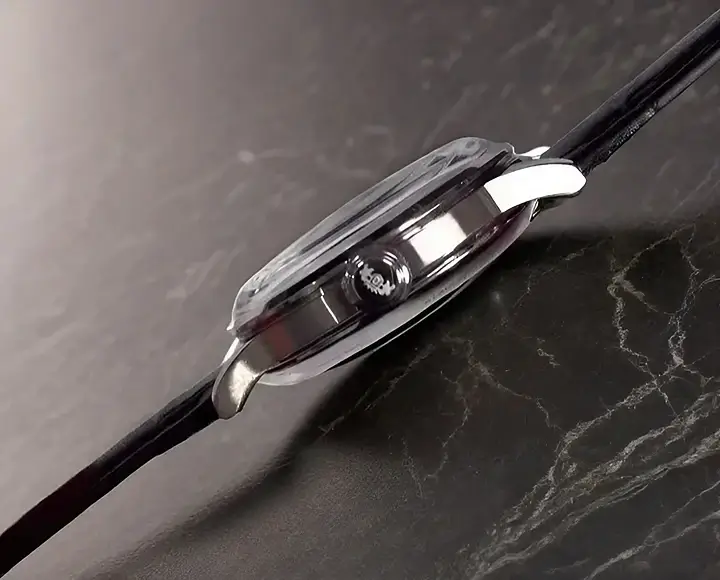 Side profile of Orient Bambino 38mm Version 7 watch showing slim case design and crown on dark gray marble background.