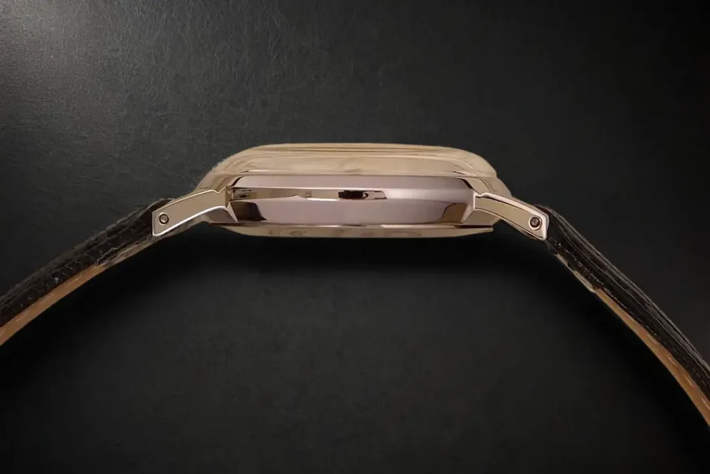 Side view of Timex Marlin Hand-Wound TW2R47900 on a black leather surface, highlighting its slim profile, case thickness, and domed acrylic crystal.
