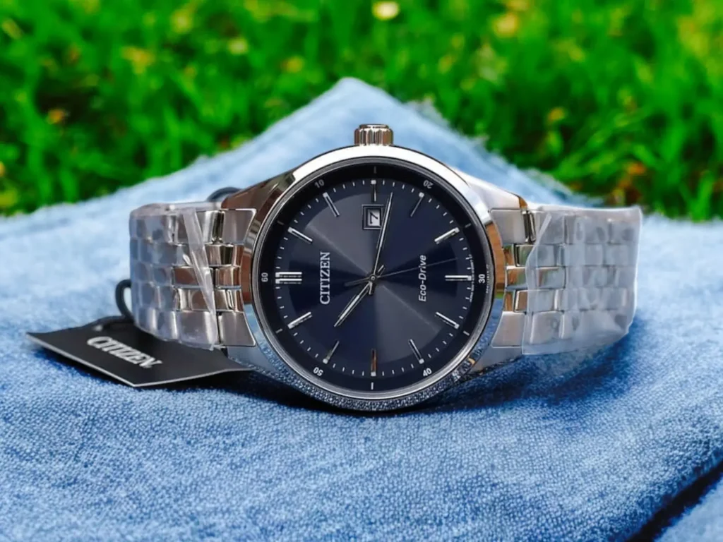 A Citizen Addysen Eco-Drive BM7251-53L rests on light-blue denim fabric, set against a blurred grass background. 