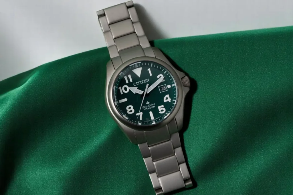 Front view of Citizen Promaster Tough BN0241-59W with green dial and titanium bracelet, laid flat on a soft, light-textured green fabric surface.
