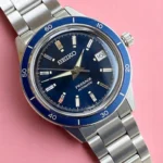 Seiko Presage Style60's SRPG05 with a blue sunburst dial and silver-tone markers, photographed against a pink background.