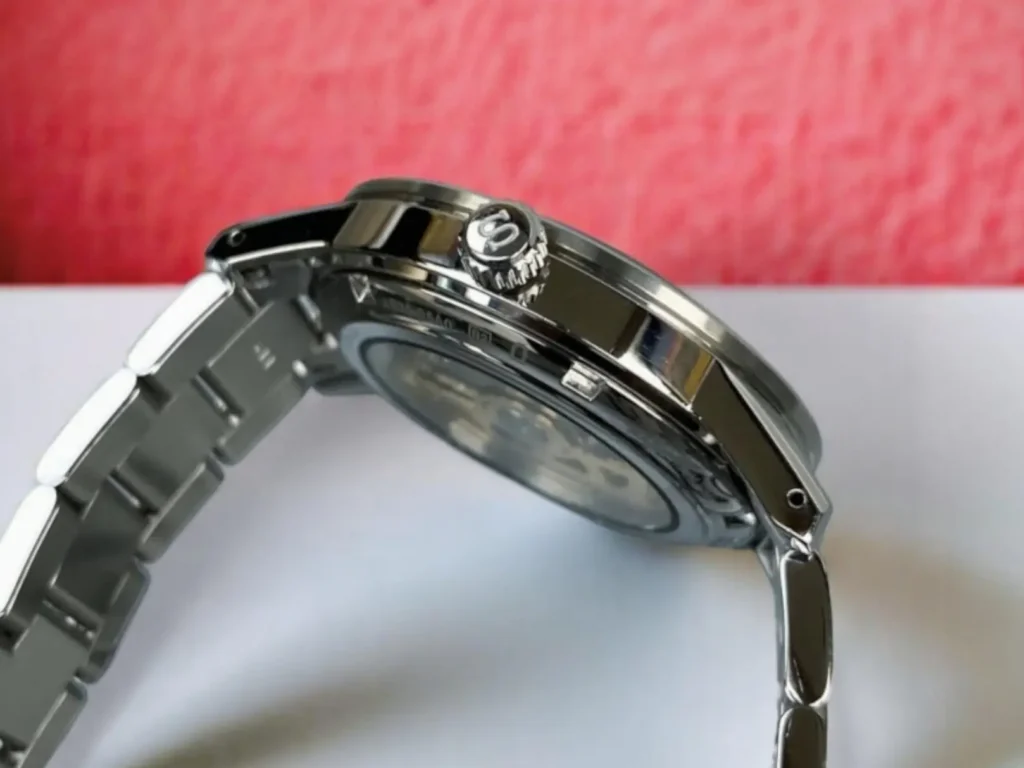 Side profile of the Seiko Presage Style60's SRPG05 highlighting its signed crown, placed on a red & white background.