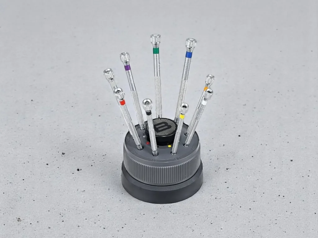 A set of precision screwdrivers in a round holder, each with a colored band on the handle.