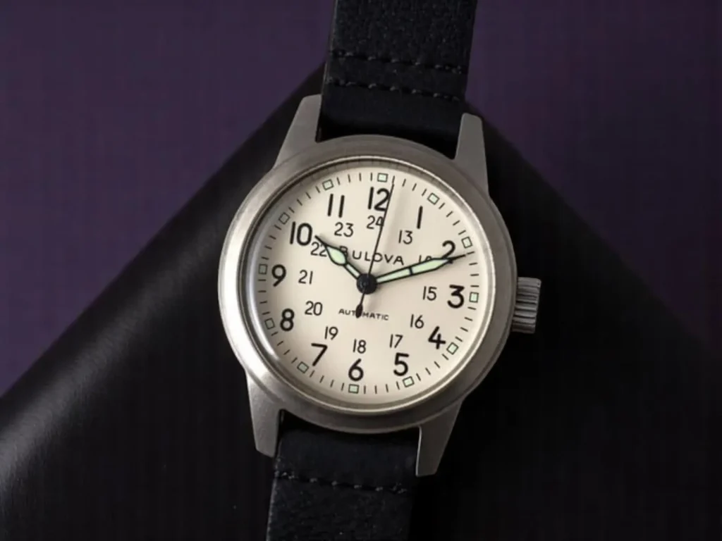 Close-up of the Bulova Hack Watch 96A246 resting on black textured leather with a dark purple background.