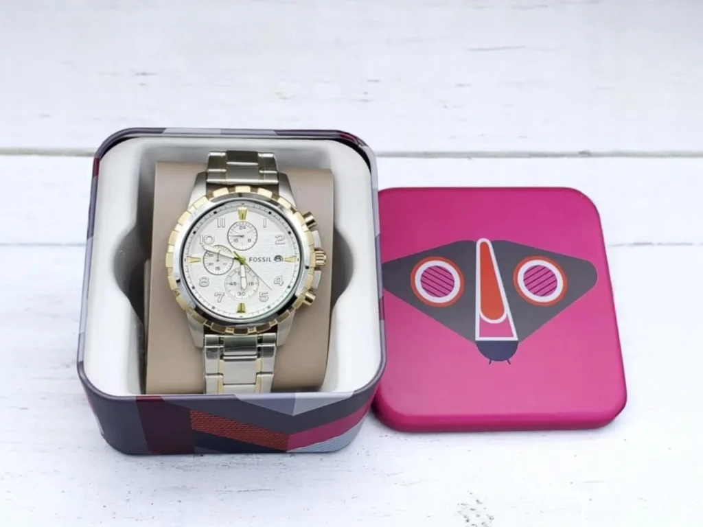 Fossil Dean Chronograph FS4795 in an open box on a white surface. The box lid is pink with a geometric owl design.