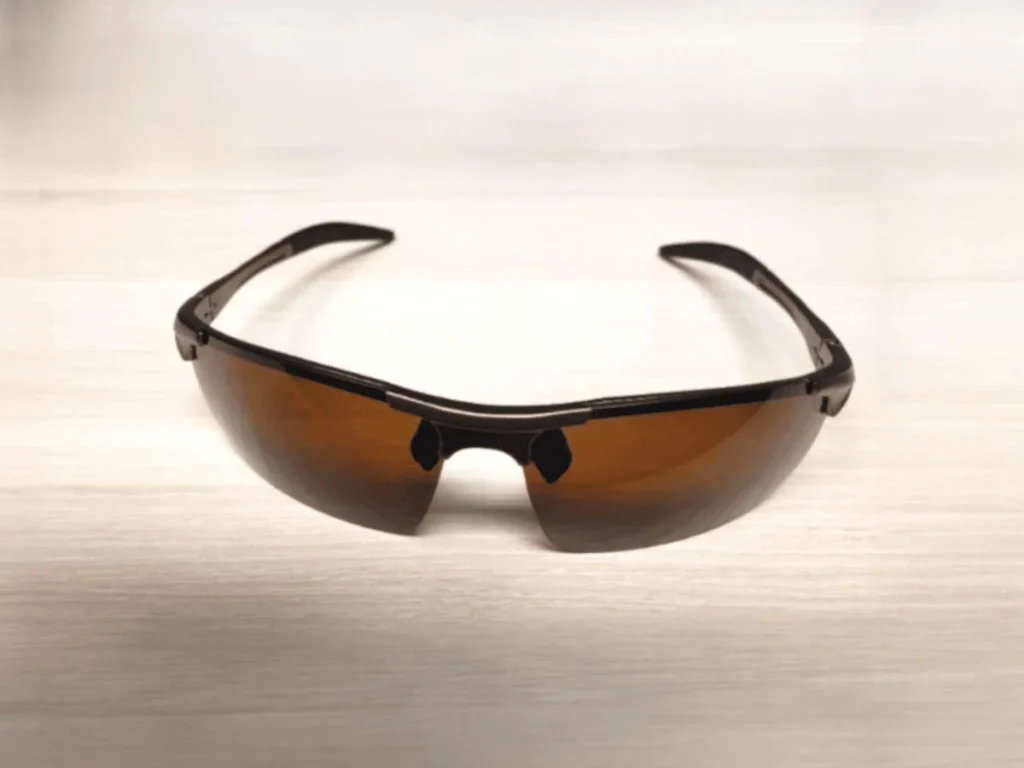 ROCKNIGHT Driving Polarized Sunglasses with brown tinted lenses, resting on a light wooden surface.