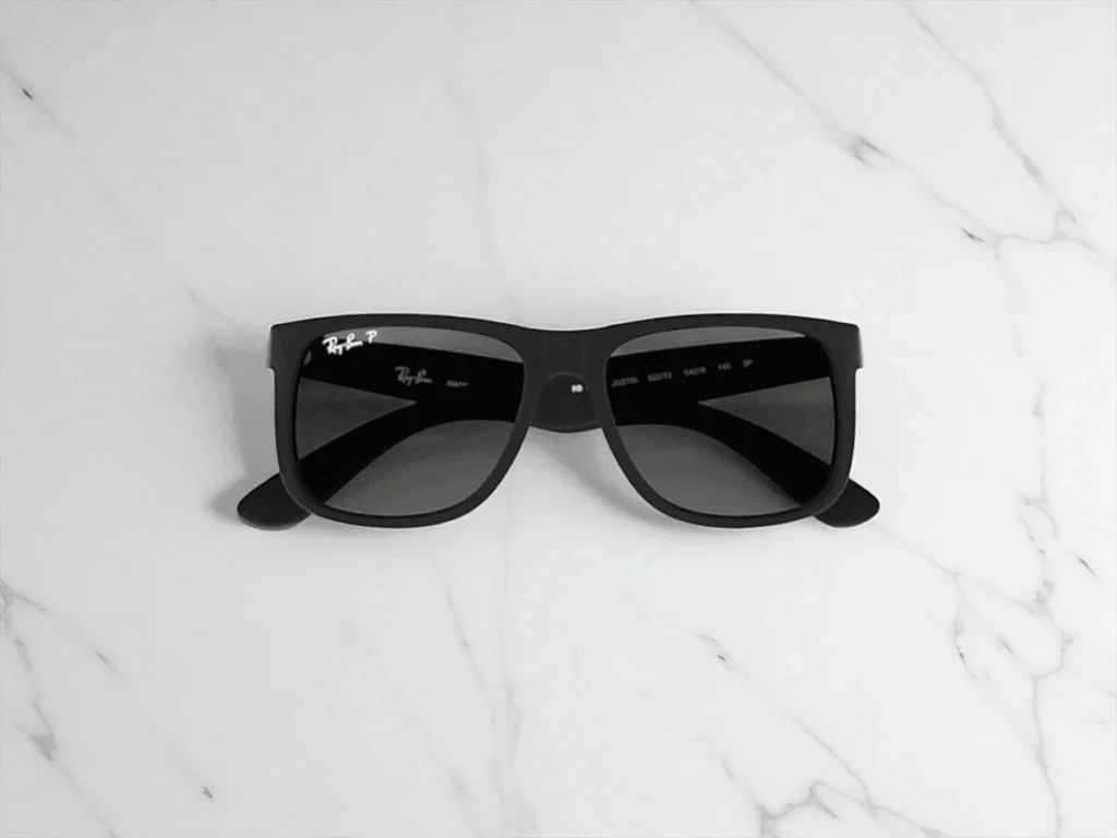 Ray-Ban RB4165 Justin Polarized sunglasses with dark lenses rests on a light marble surface.