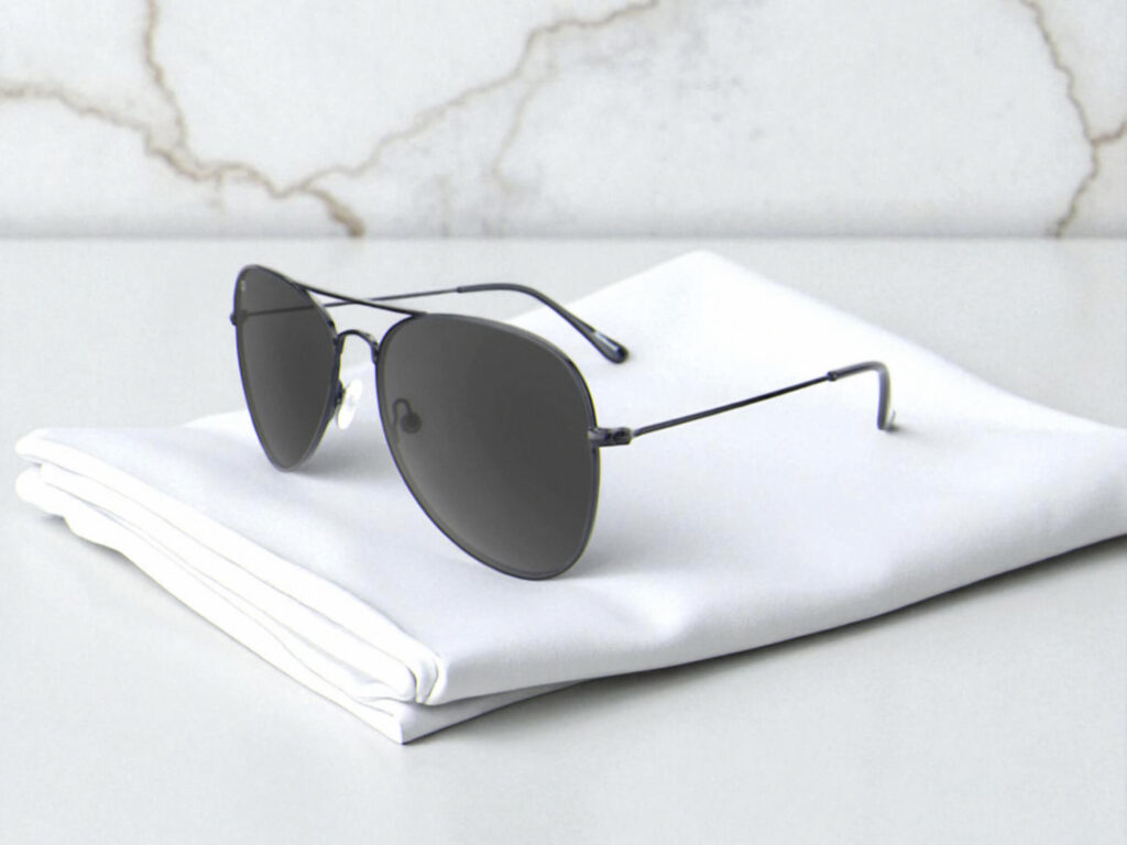 Knockaround polarized sunglasses with dark lenses and thin black frames rest on a neatly folded white cloth, set against a light marble background.