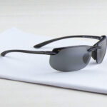 Maui Jim banyans polarized sunglasses with dark lenses rest on a folded white cloth against a light background.