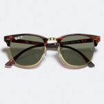 Tortoise-shell sunglasses with gold accents and green lenses, featuring a retro Clubmaster design, centered on a plain white background.