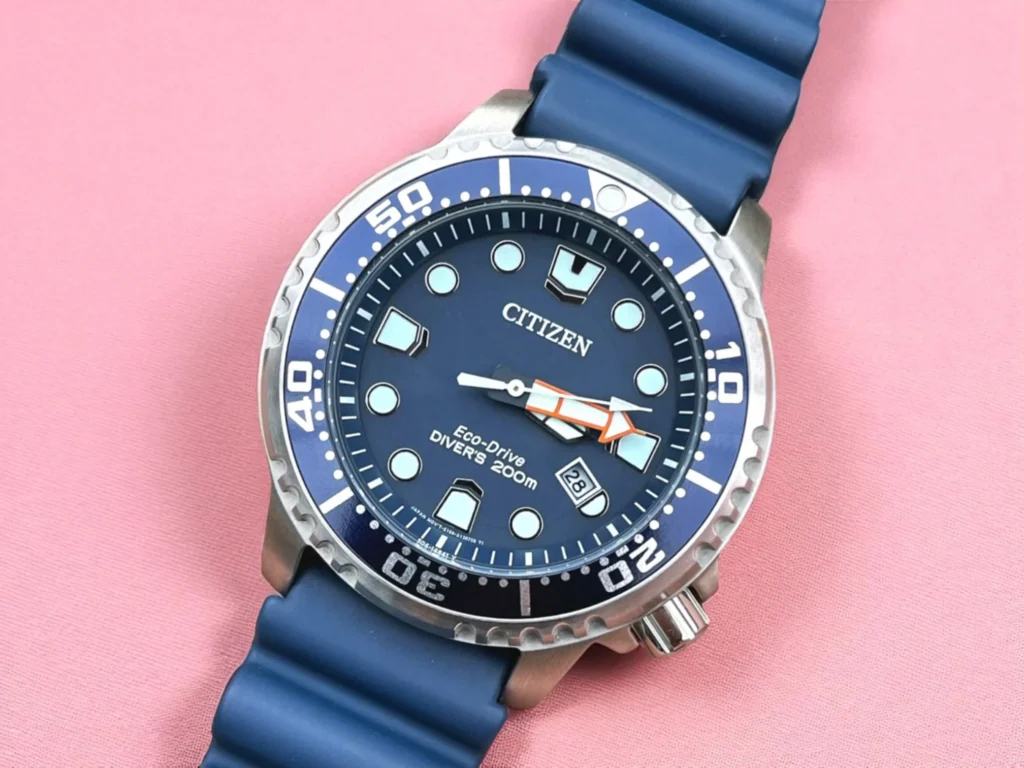 Citizen Promaster BN0151-09L with a blue dial and strap is displayed on a pink surface.
