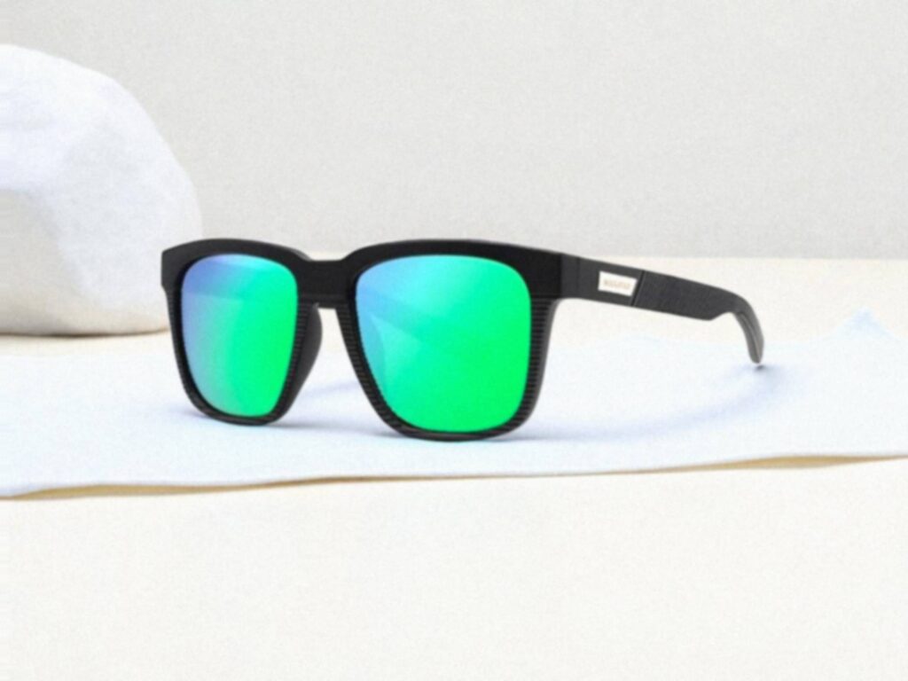 MAXJULI polarized sunglasses with reflective green lenses rest on a white surface against a light gray background.