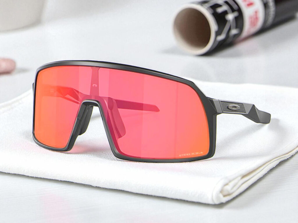 Oakley Sutro S running sunglasses with a black frame and large red lenses rest on a white cloth.