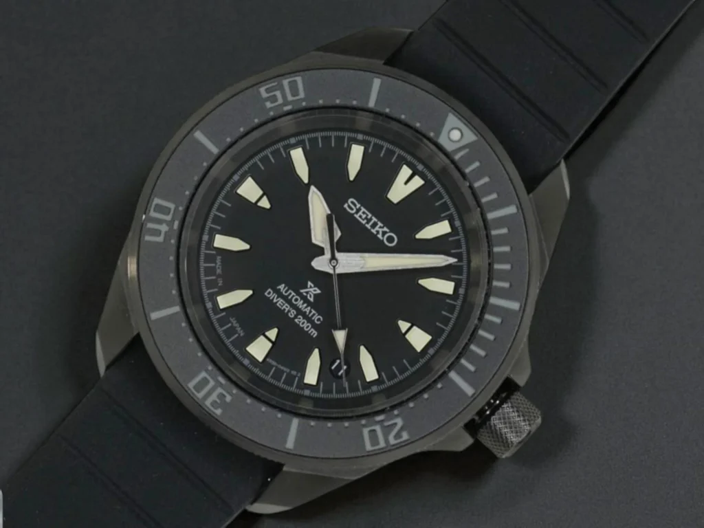 Seiko Prospex Automatic SRPL15 with luminous markers and hands, resting on a black surface.