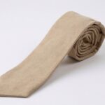A neatly rolled Proper Materials cotton-chambray tie in beige, displayed against a white background.