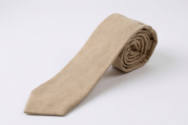 A neatly rolled Proper Materials cotton-chambray tie in beige, displayed against a white background.