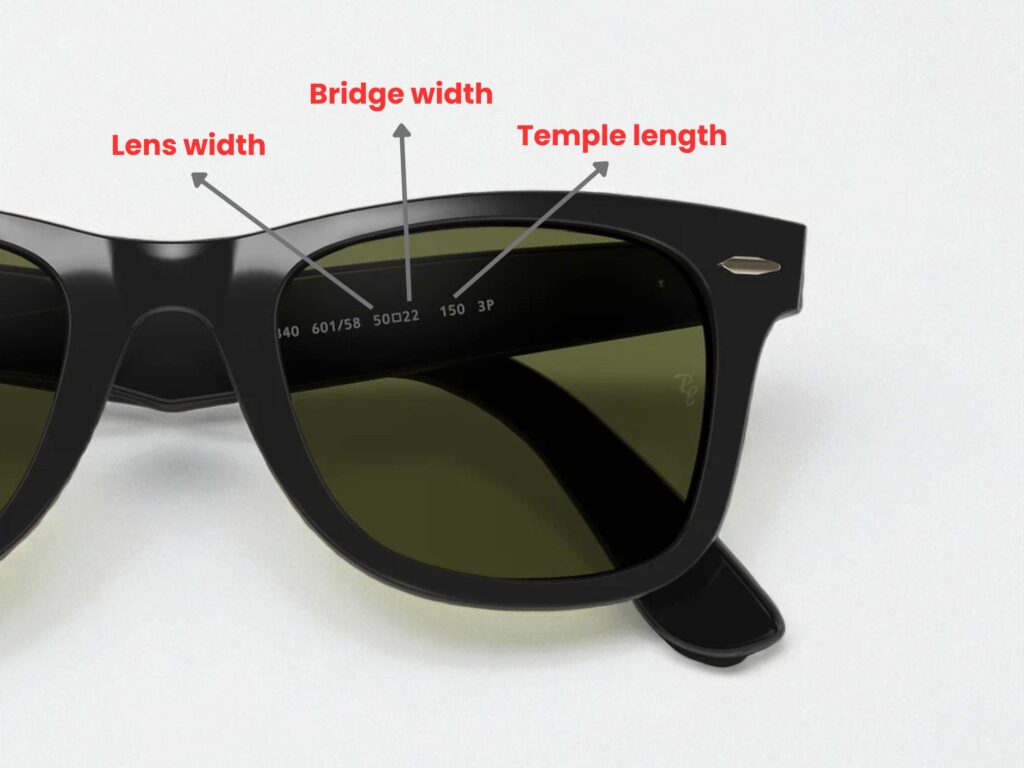 Close-up of black sunglasses highlighting lens width, bridge width, and temple length with arrows and labels. Sunglasses have dark green lenses.