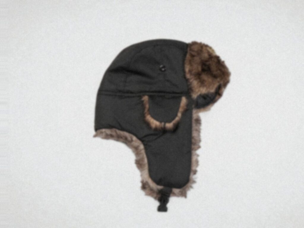 A trapper hat with brown faux fur lining and ear flaps, set against a plain light background. 