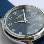 Close-up of a Seiko automatic watch featuring a polished case, a textured dark blue dial, silver hour markers, and sleek hands.