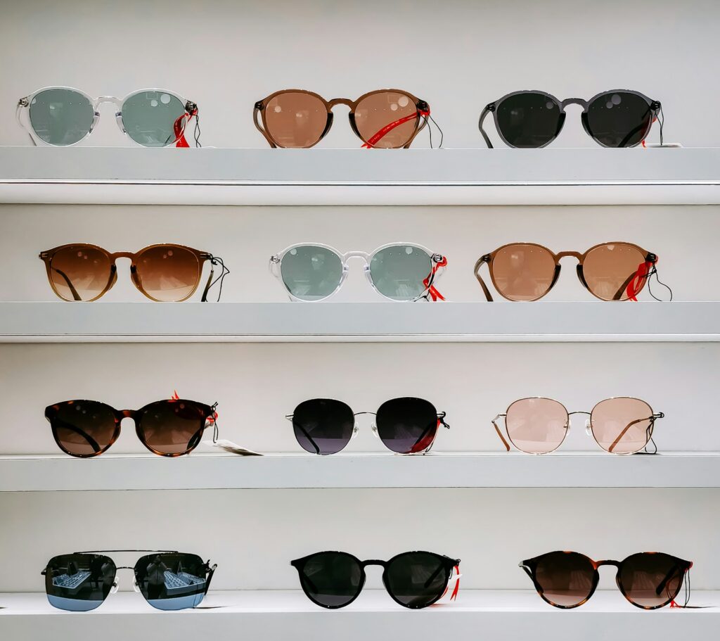 Four shelves display an array of stylish sunglasses, featuring various shapes, colors, and lenses.
