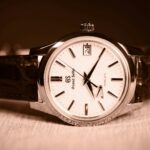 Grand Seiko Spring Drive wristwatch with a textured white dial, silver hour markers, and brown leather strap.