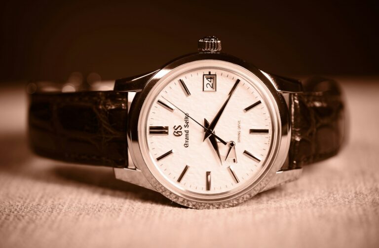 Grand Seiko Spring Drive wristwatch with a textured white dial, silver hour markers, and brown leather strap.