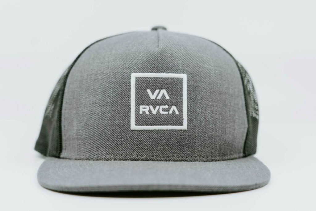 Gray snapback cap with a mesh back, featuring a white square logo with "VA RVCA" text on the front.