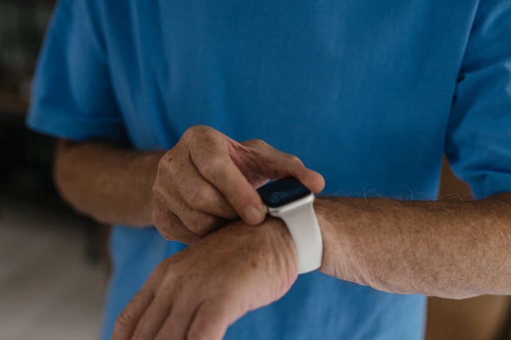 A person in a blue shirt interacts with a smartwatch on their wrist, touching the screen with focus and curiosity