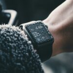 Close-up of a wrist wearing a smartwatch with water droplets on its screen, displaying a digital time.