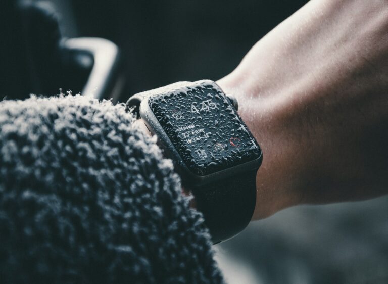 Close-up of a wrist wearing a smartwatch with water droplets on its screen, displaying a digital time.
