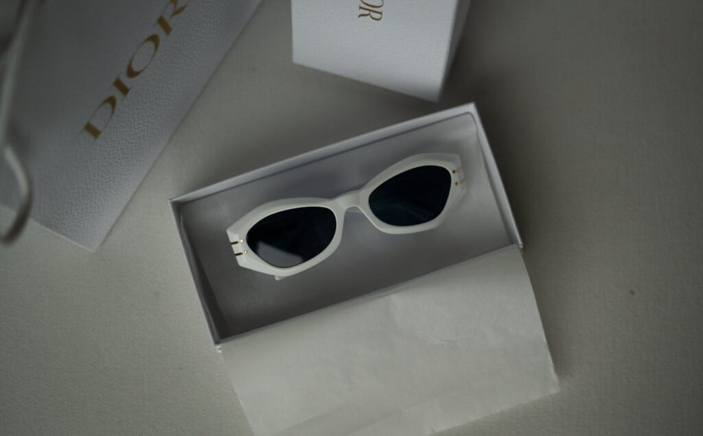 White cat-eye sunglasses with dark lenses in a designer Dior box. The presentation conveys luxury and elegance with a minimalistic style.