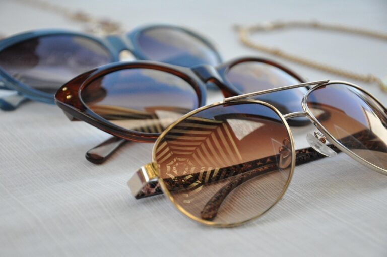 Three pairs of sunglasses with different lens materials on a white surface: blue, tortoiseshell, and aviator.