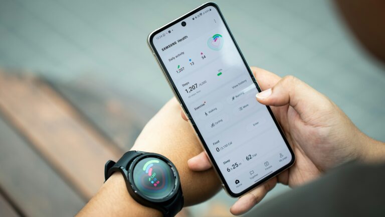 Person holding a android smartphone displaying a fitness app with health stats. Another hand wears a smartwatch showing similar data.