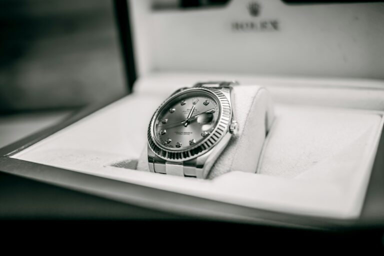 A luxury used Rolex watch with a metal band and diamond hour markers is elegantly displayed in an open, cushioned box.